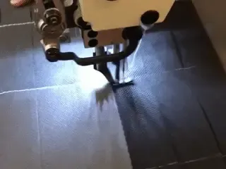 Nahaufnahme einer Nähmaschine bei der handgefertigten Produktion von robusten Vlies-Stecktafeln für die Bauprozesssteuerung.